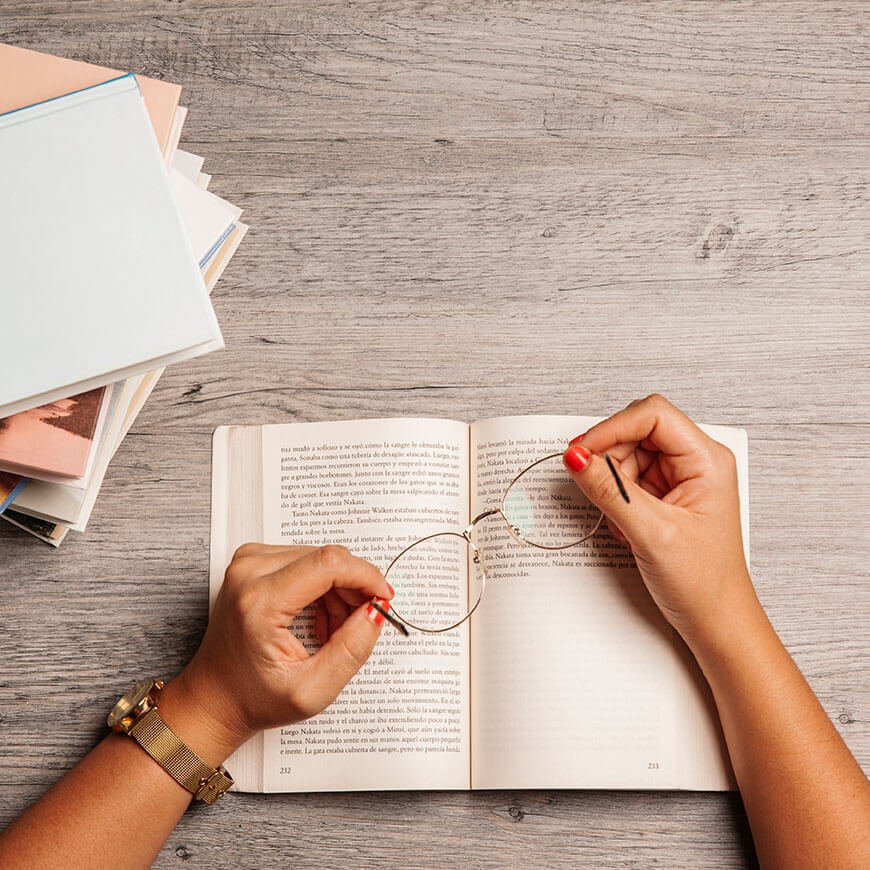 Hands holding a book and glasses